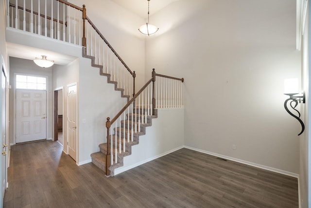 entryway with a towering ceiling and dark hardwood / wood-style flooring