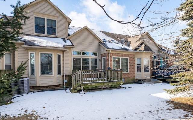 snow covered rear of property featuring central AC unit