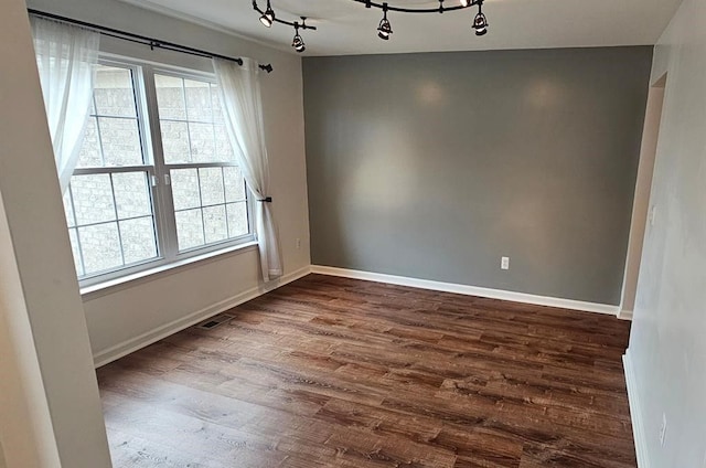 empty room featuring hardwood / wood-style flooring, rail lighting, and a healthy amount of sunlight