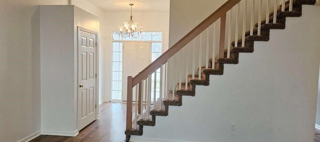 staircase featuring wood-type flooring and an inviting chandelier