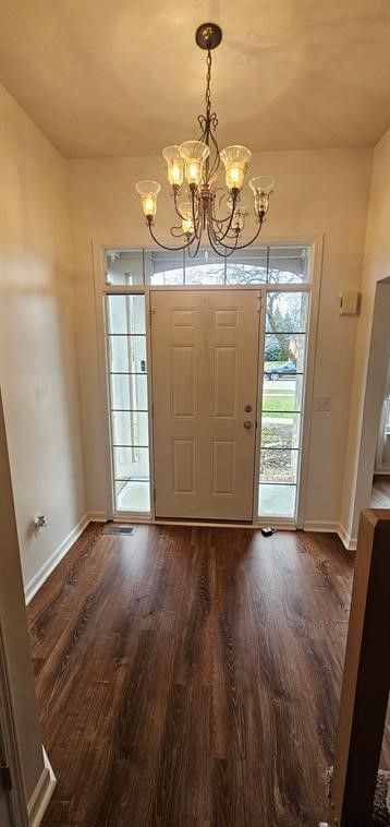 foyer entrance with dark hardwood / wood-style floors and a chandelier