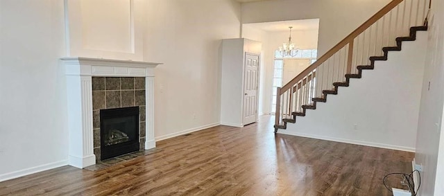 unfurnished living room featuring a tile fireplace, dark wood-type flooring, and an inviting chandelier