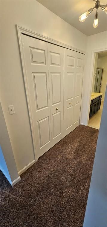 unfurnished bedroom featuring ceiling fan, dark carpet, and a closet