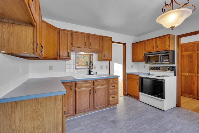 kitchen featuring white range with electric cooktop, sink, and hanging light fixtures