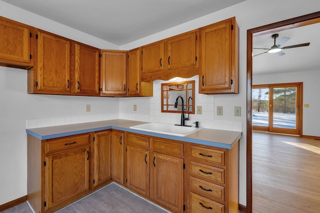 kitchen featuring light wood-type flooring, ceiling fan, sink, and backsplash