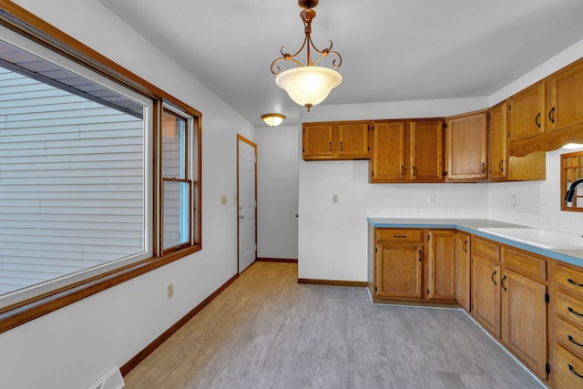 kitchen featuring sink, hanging light fixtures, and light wood-type flooring