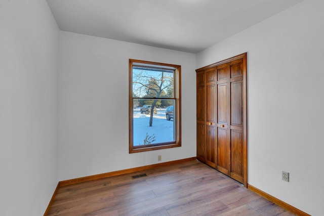 unfurnished bedroom with light wood-type flooring and a closet