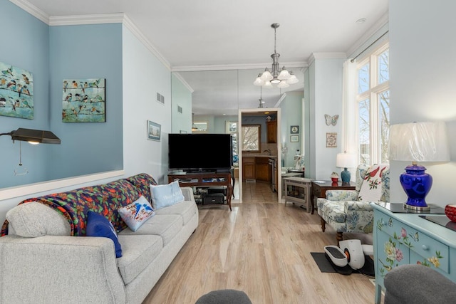 living room featuring light hardwood / wood-style floors, crown molding, and an inviting chandelier