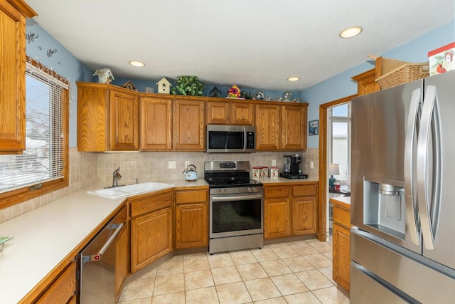 kitchen with sink, backsplash, light tile patterned floors, and stainless steel appliances