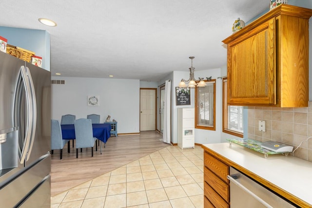 kitchen with decorative light fixtures, tasteful backsplash, light tile patterned floors, an inviting chandelier, and stainless steel appliances