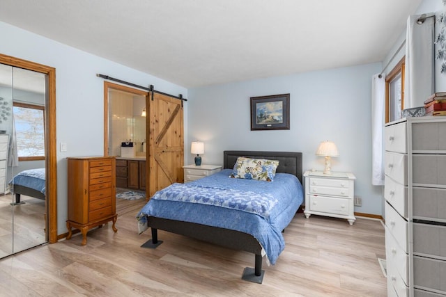 bedroom featuring multiple windows, light hardwood / wood-style flooring, and a barn door