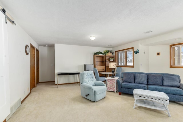 living room featuring a barn door, a textured ceiling, and light carpet