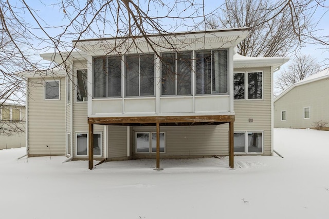 snow covered property featuring a sunroom