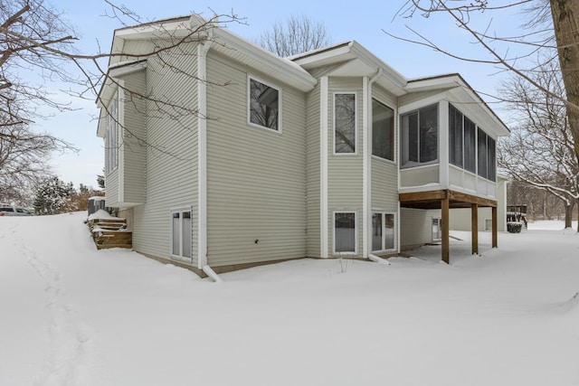 view of snowy exterior with a sunroom