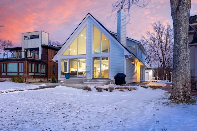 snow covered house featuring a garage and a balcony