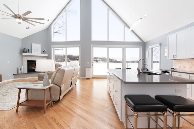 kitchen with white cabinetry, a kitchen bar, sink, and light wood-type flooring