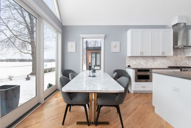 dining space featuring vaulted ceiling and light hardwood / wood-style flooring