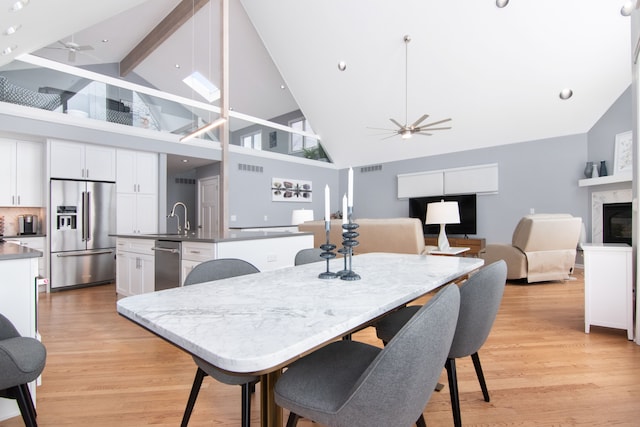 dining space featuring ceiling fan, sink, a high end fireplace, and light hardwood / wood-style flooring