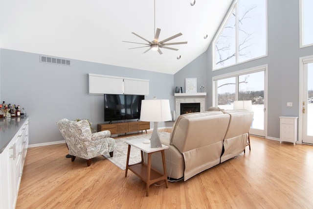 living room featuring light hardwood / wood-style flooring, high vaulted ceiling, and ceiling fan