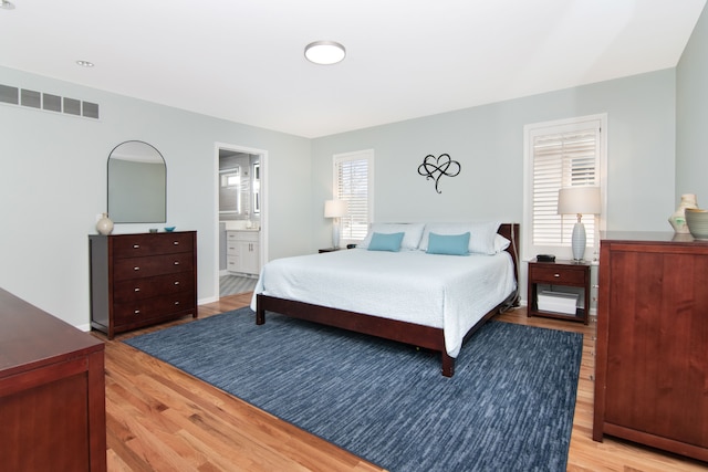 bedroom featuring light hardwood / wood-style floors and ensuite bathroom