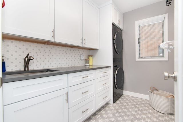 laundry room with cabinets, stacked washing maching and dryer, and sink