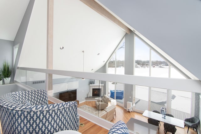 living room with beam ceiling, high vaulted ceiling, and light wood-type flooring