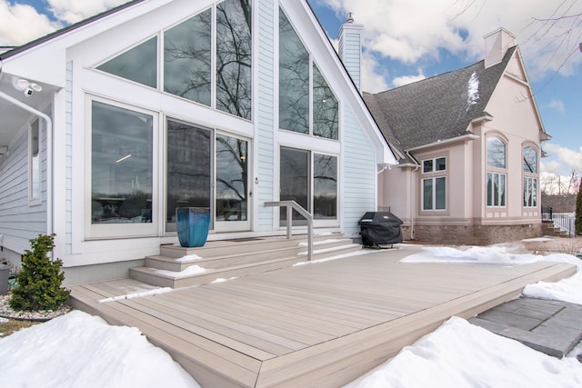 snow covered back of property with a wooden deck