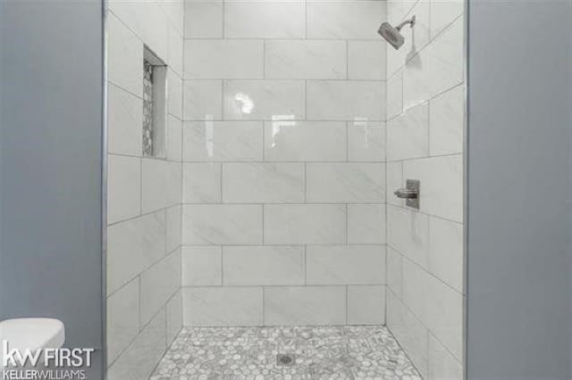 bathroom with toilet and tiled shower