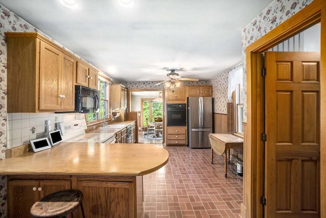 kitchen featuring black appliances, tasteful backsplash, sink, kitchen peninsula, and ceiling fan