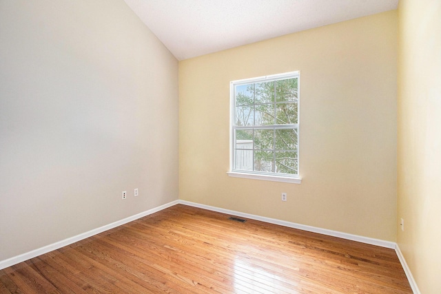 spare room featuring lofted ceiling and light wood-type flooring