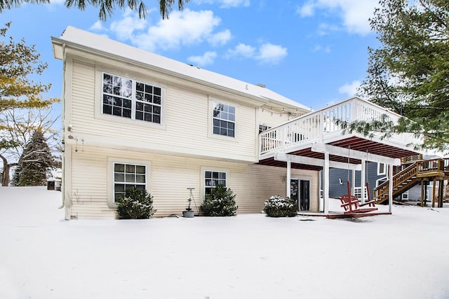 snow covered rear of property featuring a wooden deck and a pergola