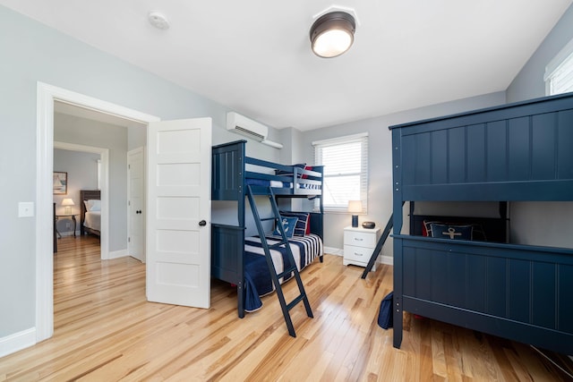 bedroom featuring light hardwood / wood-style floors and an AC wall unit