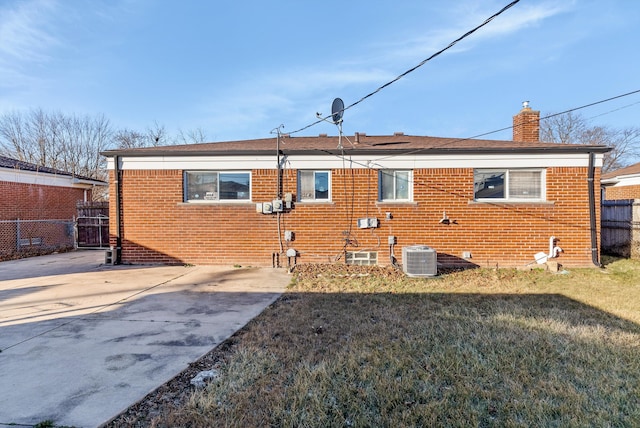 back of house featuring central AC unit and a lawn