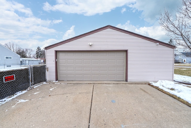 snow covered garage with a detached garage and fence