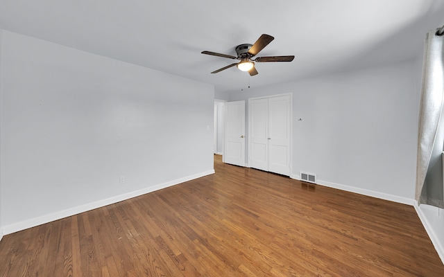 unfurnished bedroom featuring a closet, visible vents, ceiling fan, wood finished floors, and baseboards