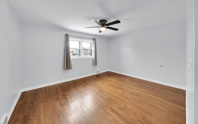 empty room featuring ceiling fan, visible vents, hardwood / wood-style flooring, and baseboards