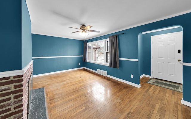 interior space featuring arched walkways, visible vents, hardwood / wood-style floors, a ceiling fan, and baseboards