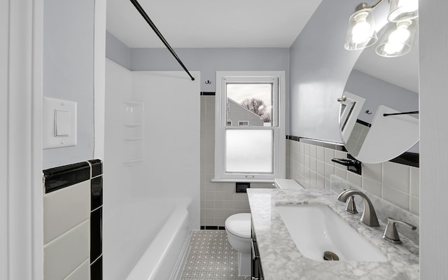 bathroom featuring toilet, tile patterned flooring, bathtub / shower combination, vanity, and tile walls