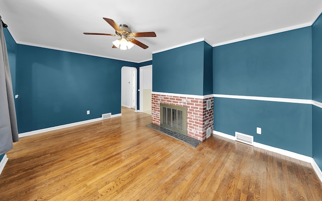 unfurnished living room with a brick fireplace, baseboards, visible vents, and ornamental molding