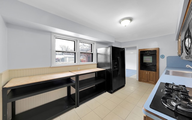 kitchen featuring light countertops, a sink, black appliances, and light tile patterned floors