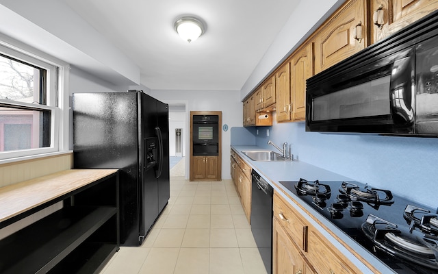 kitchen featuring brown cabinets, light countertops, light tile patterned flooring, a sink, and black appliances