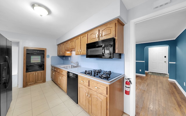 kitchen featuring baseboards, light countertops, black appliances, a sink, and a warming drawer