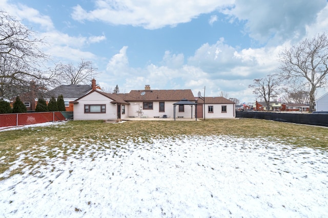 rear view of house featuring a yard, fence, a chimney, and a gazebo