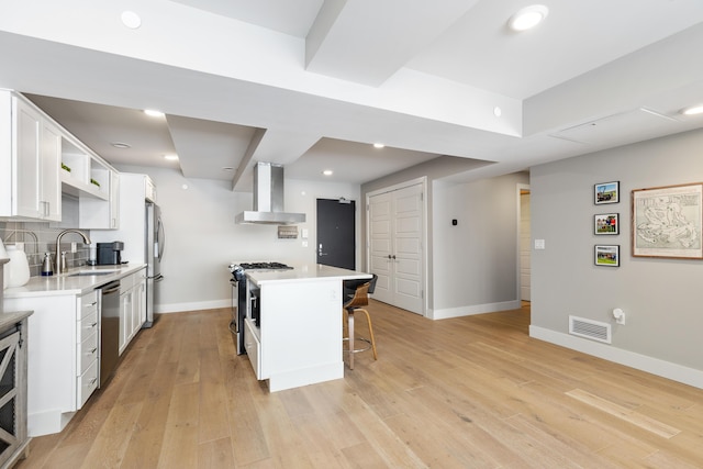 kitchen with appliances with stainless steel finishes, extractor fan, a kitchen island, white cabinetry, and sink