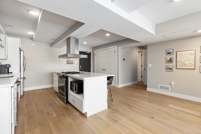 kitchen featuring light hardwood / wood-style floors, appliances with stainless steel finishes, white cabinetry, island range hood, and a breakfast bar area