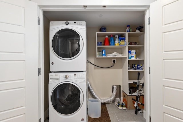 laundry area featuring stacked washer / dryer and tile patterned flooring