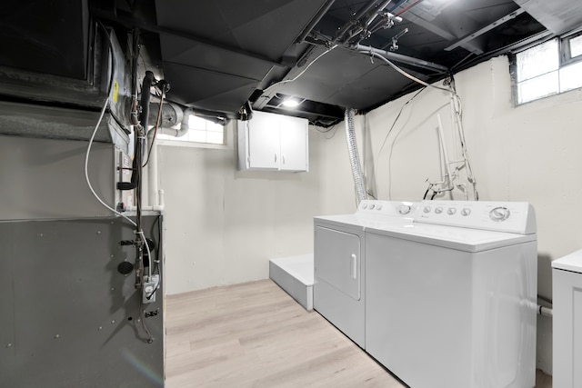 laundry room with a healthy amount of sunlight, washing machine and dryer, and light hardwood / wood-style flooring