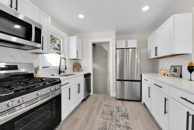 kitchen featuring backsplash, appliances with stainless steel finishes, sink, and white cabinets