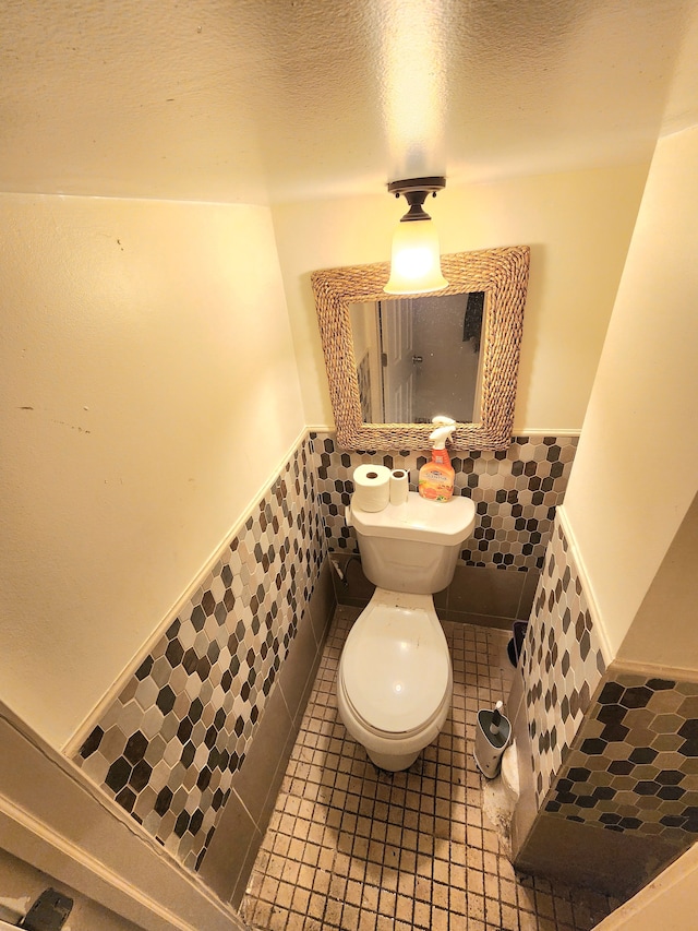 bathroom featuring tile patterned floors, toilet, and tile walls