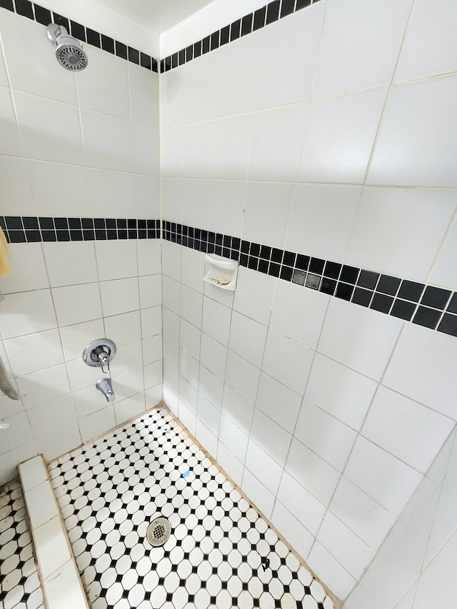 bathroom with a tile shower and tile patterned floors